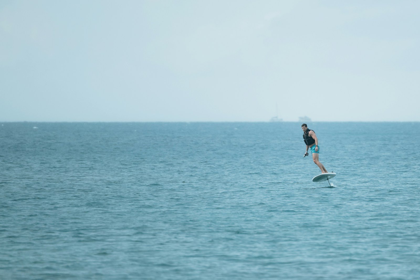 Un pratiquant de flyboard en vol au-dessus de l'eau, debout sur sa planche
