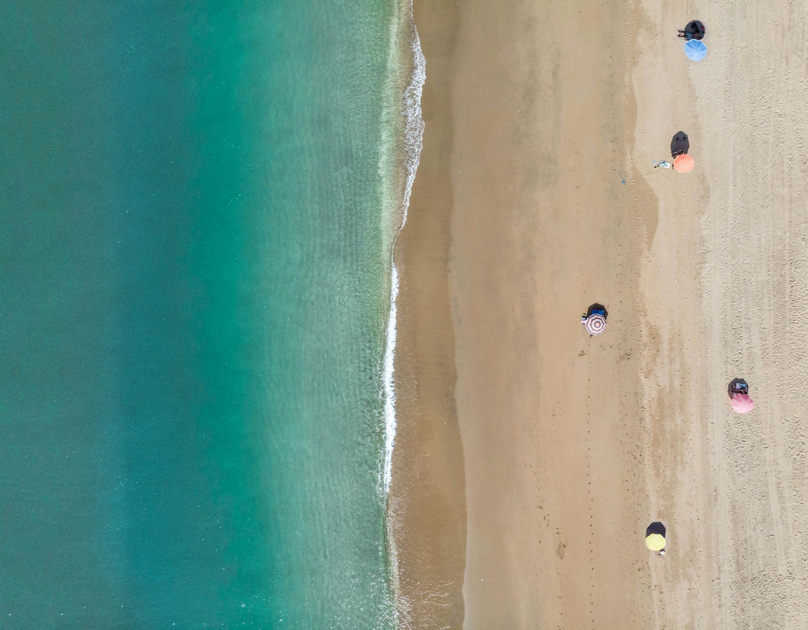 Longue plage de sable rectiligne bordée d'étangs, vue depuis la mer