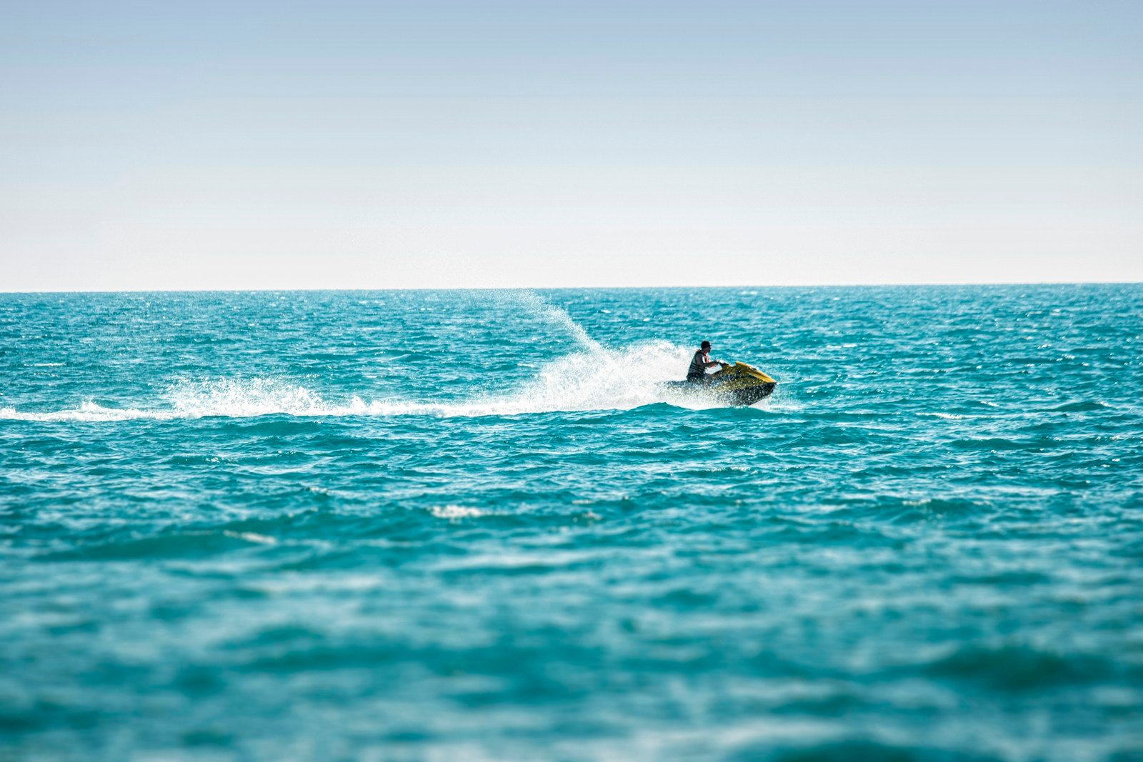 Un jet-ski lancé au large, la gerbe d'eau derrière la coque