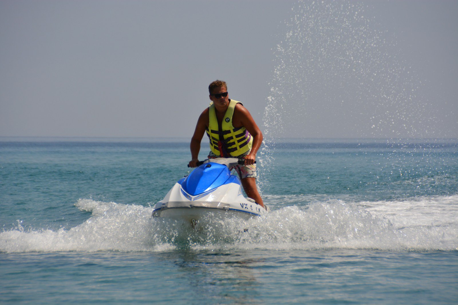 Un jet-ski lancé sur une mer turquoise le long d'une côte méditerranéenne