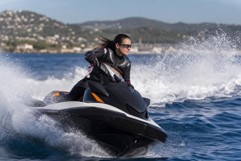 Une pilote en combinaison néoprène et gilet de flottabilité, lancée sur un jet-ski au large